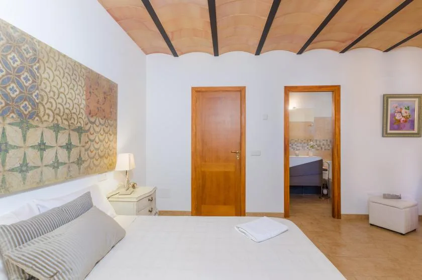 A bedroom with a bed, patterned wall decoration, and wooden doors.
