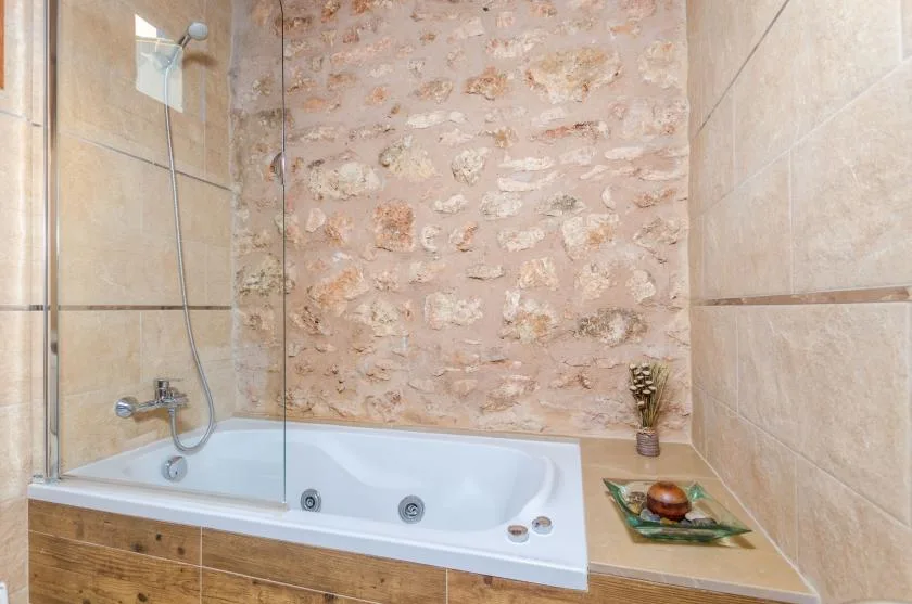 A bathroom with a bathtub beneath a stone-patterned wall.