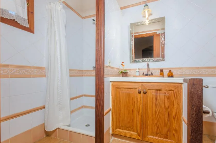 A tiled bathroom with a shower curtain and a wooden vanity beneath a mirror.