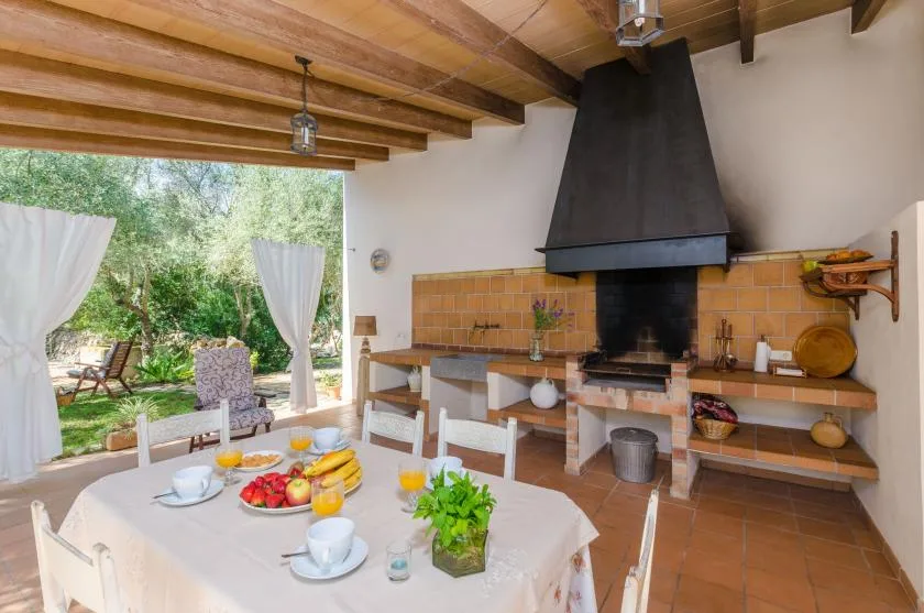 A dining area with a set table beside a large built-in fireplace.