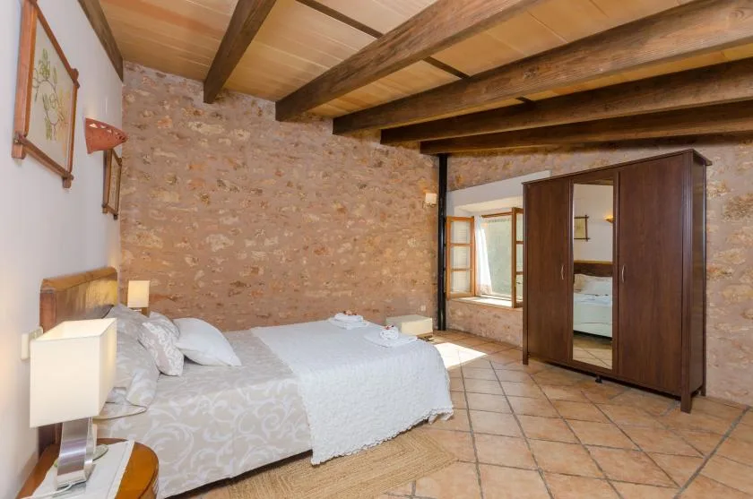 A bedroom with two beds, exposed wooden ceiling beams, and a wardrobe.
