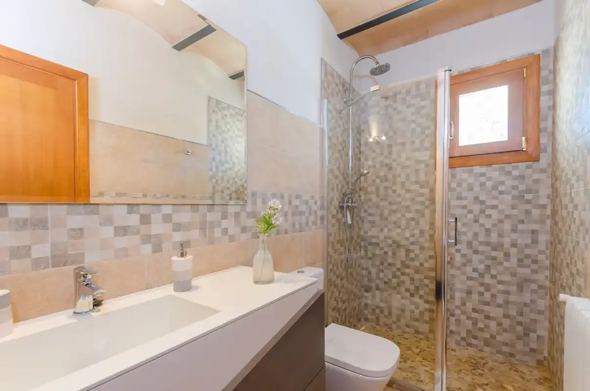 A bathroom with a sink, mirror, and glass shower.