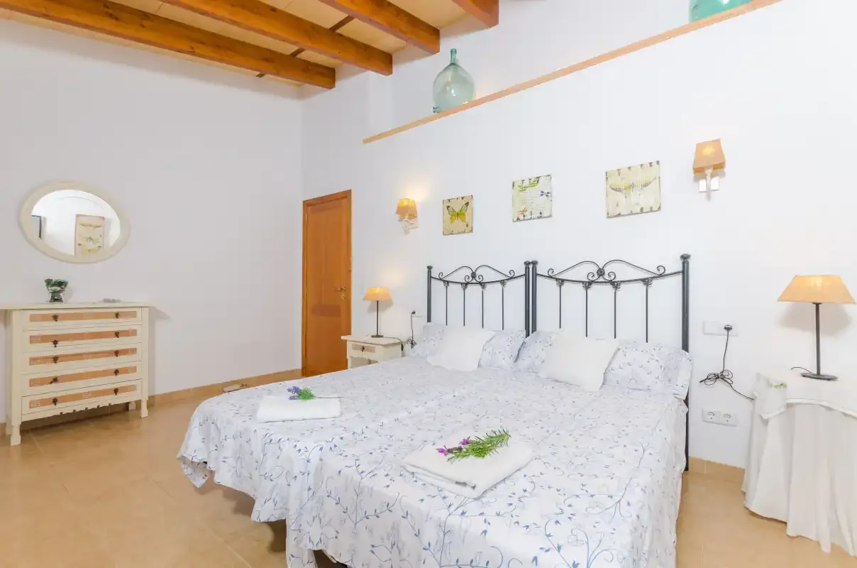 A bright bedroom with a bed dressed in white patterned bedding.