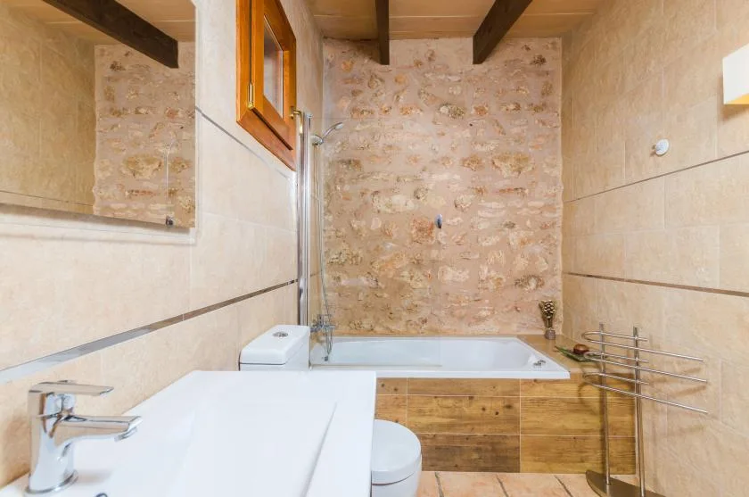 A bathroom with a bathtub, sink, and exposed stone wall.