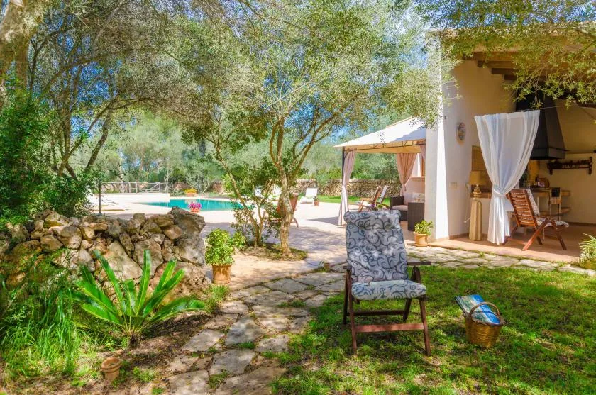 A garden patio with outdoor seating beside a swimming pool.