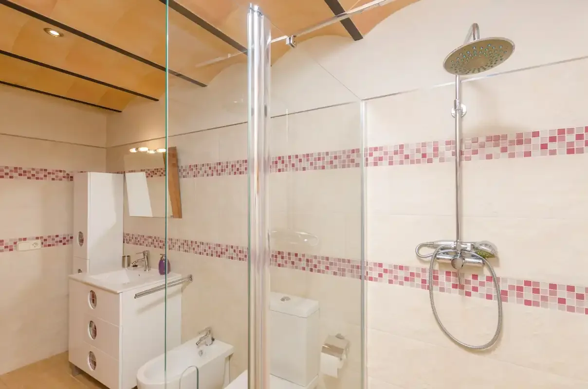 A bathroom with a shower and sink against tiled walls.