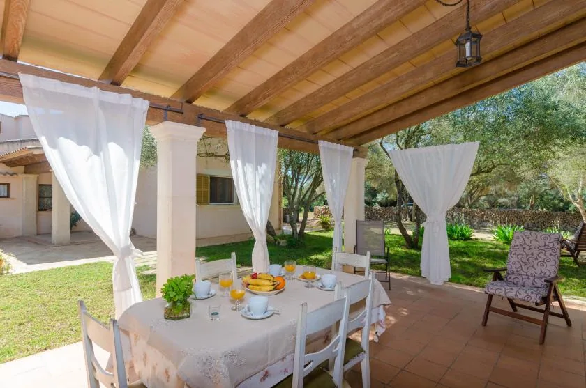 A covered patio dining area with a table set beside the garden.
