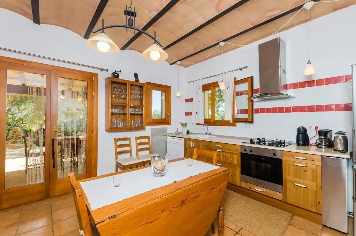 A kitchen with wooden cabinets, a dining table, and glass doors opening to a patio.