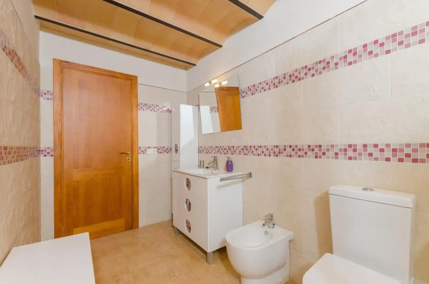 A tiled bathroom with a vanity, mirror, toilet, and bidet.