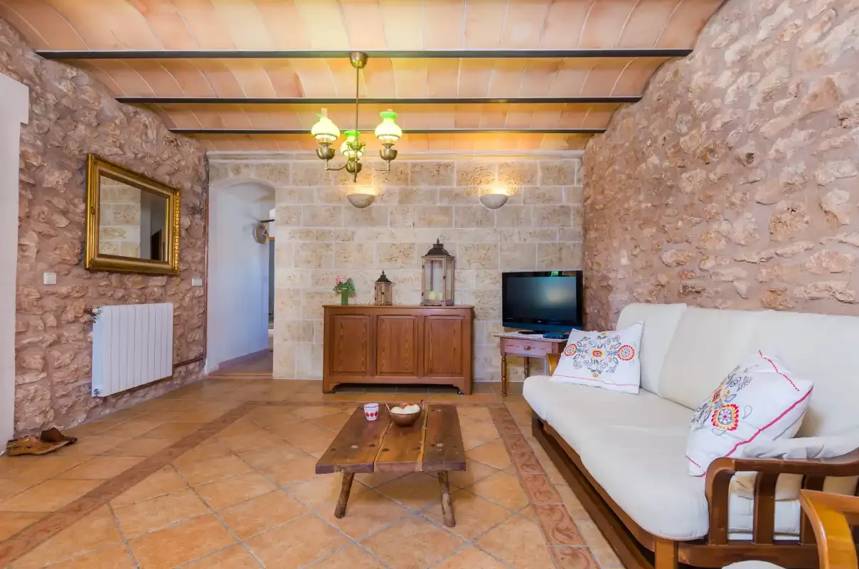 A stone-walled living room with seating and a television.