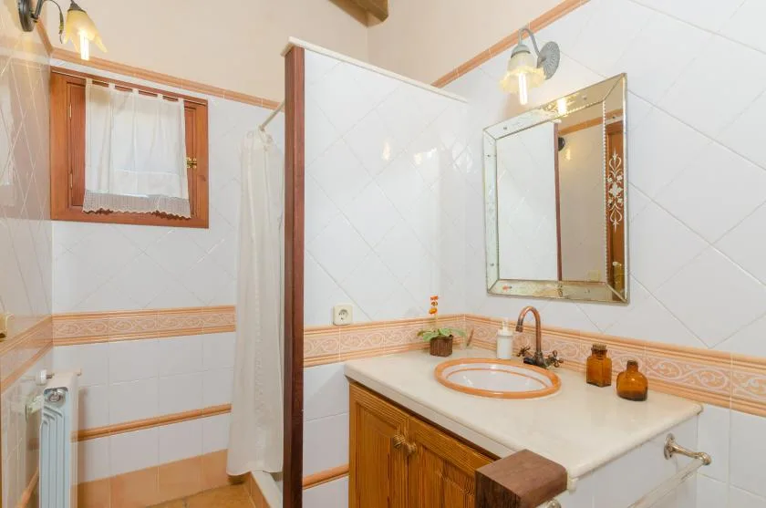 A tiled bathroom with a sink, mirror, and shower curtain.