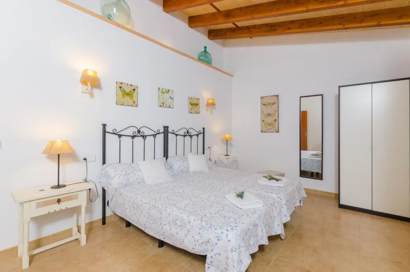 A bedroom with a double bed, bedside tables, and a white wardrobe.