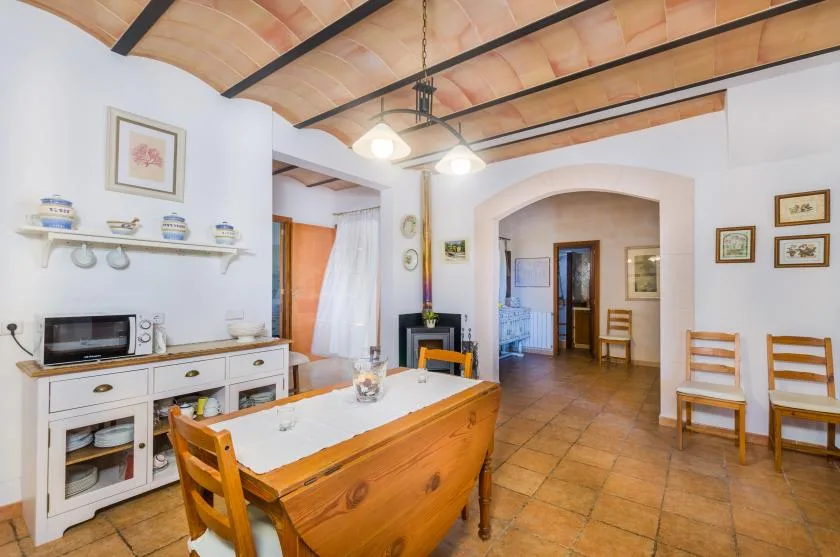 A rustic dining area with a wooden table beneath exposed ceiling beams.
