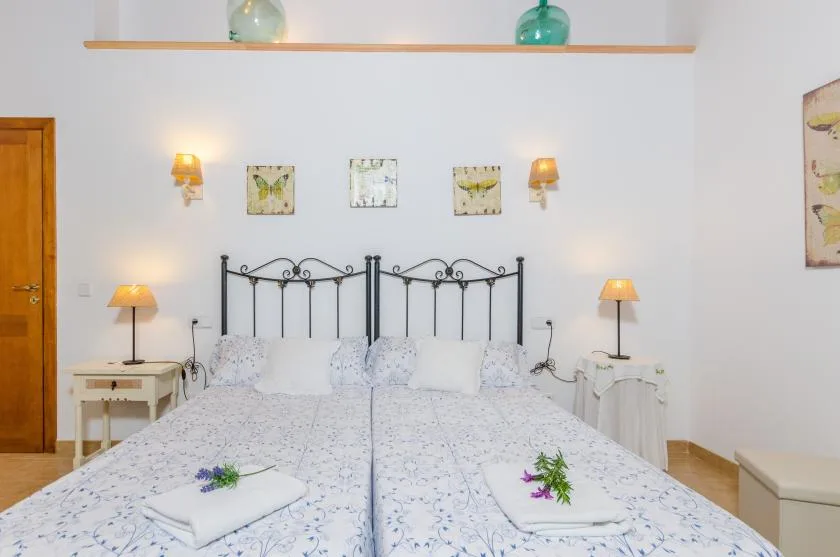 A bedroom with two beds, floral bedding, and matching bedside tables.