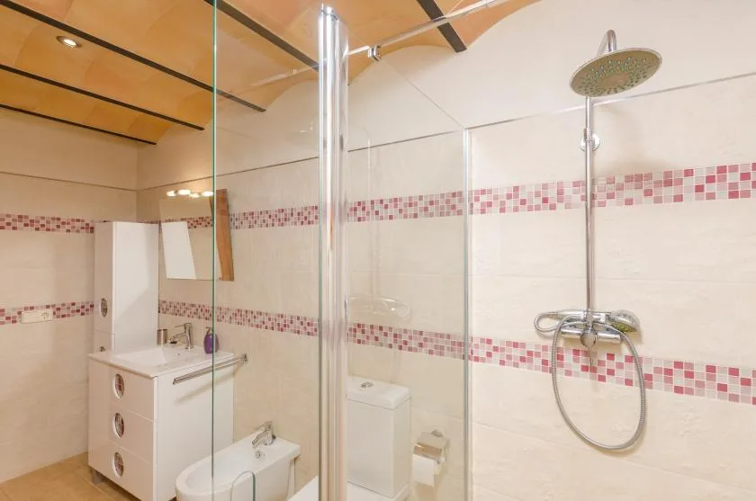 A tiled bathroom with a glass shower and wall-mounted showerhead.