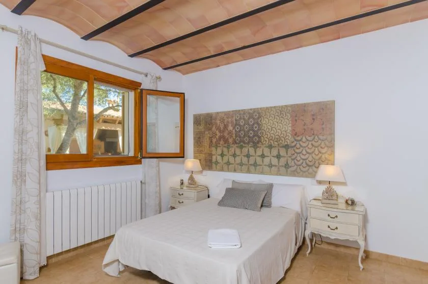 A bedroom with a bed beneath patterned wall art and beside a window.