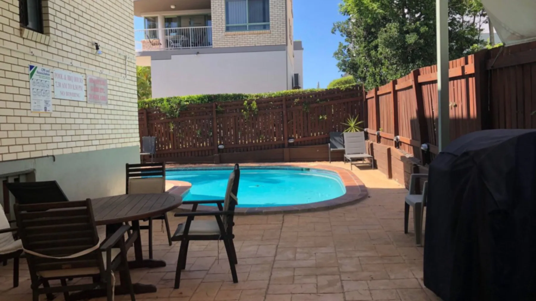 Zona de piscina al aire libre con asientos de patio y una cerca de madera.