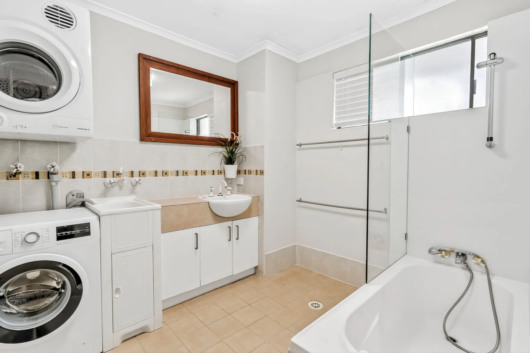 Un baño con bañera, mampara de vidrio y lavabo.