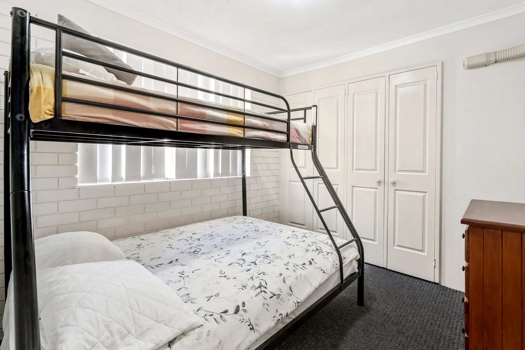 Dormitorio con literas, una cama inferior estampada y puertas blancas con paneles.