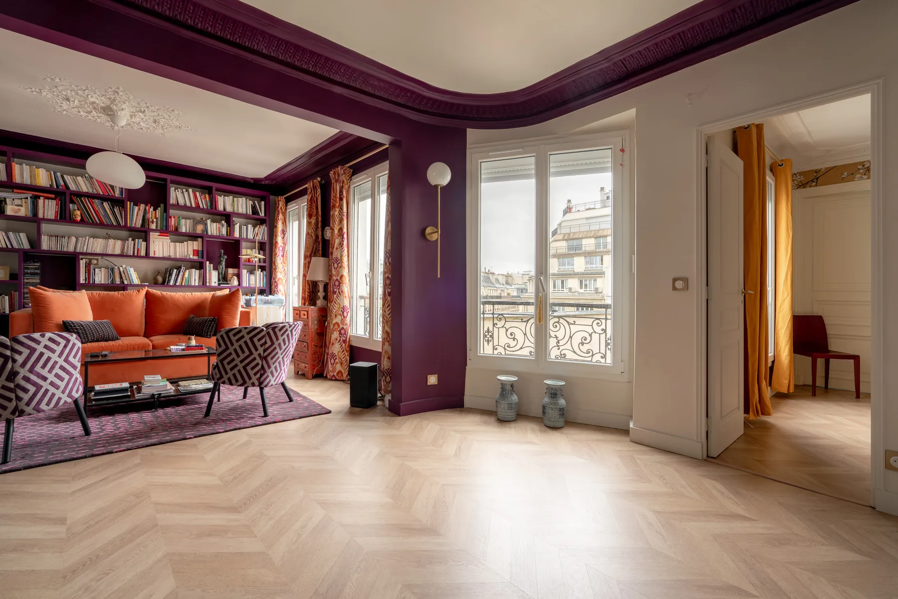 Una sala de estar con estanterías, asientos y ventanas grandes.