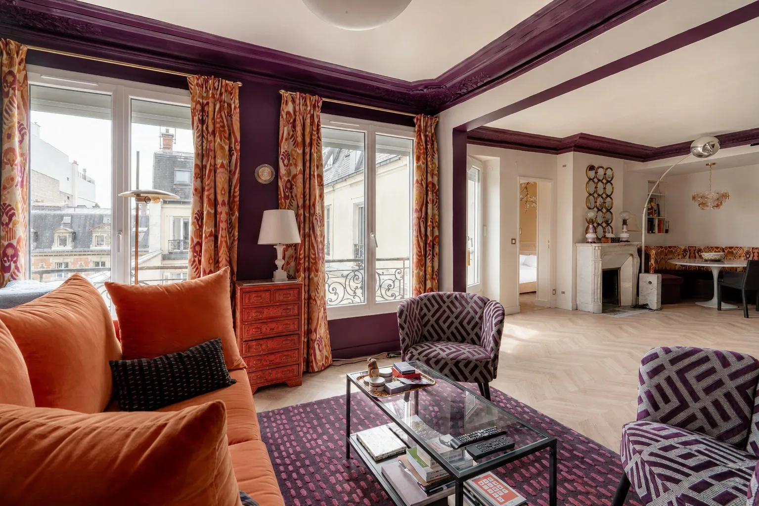 Una sala de estar con asientos, una mesa de centro de cristal y ventanas altas.
