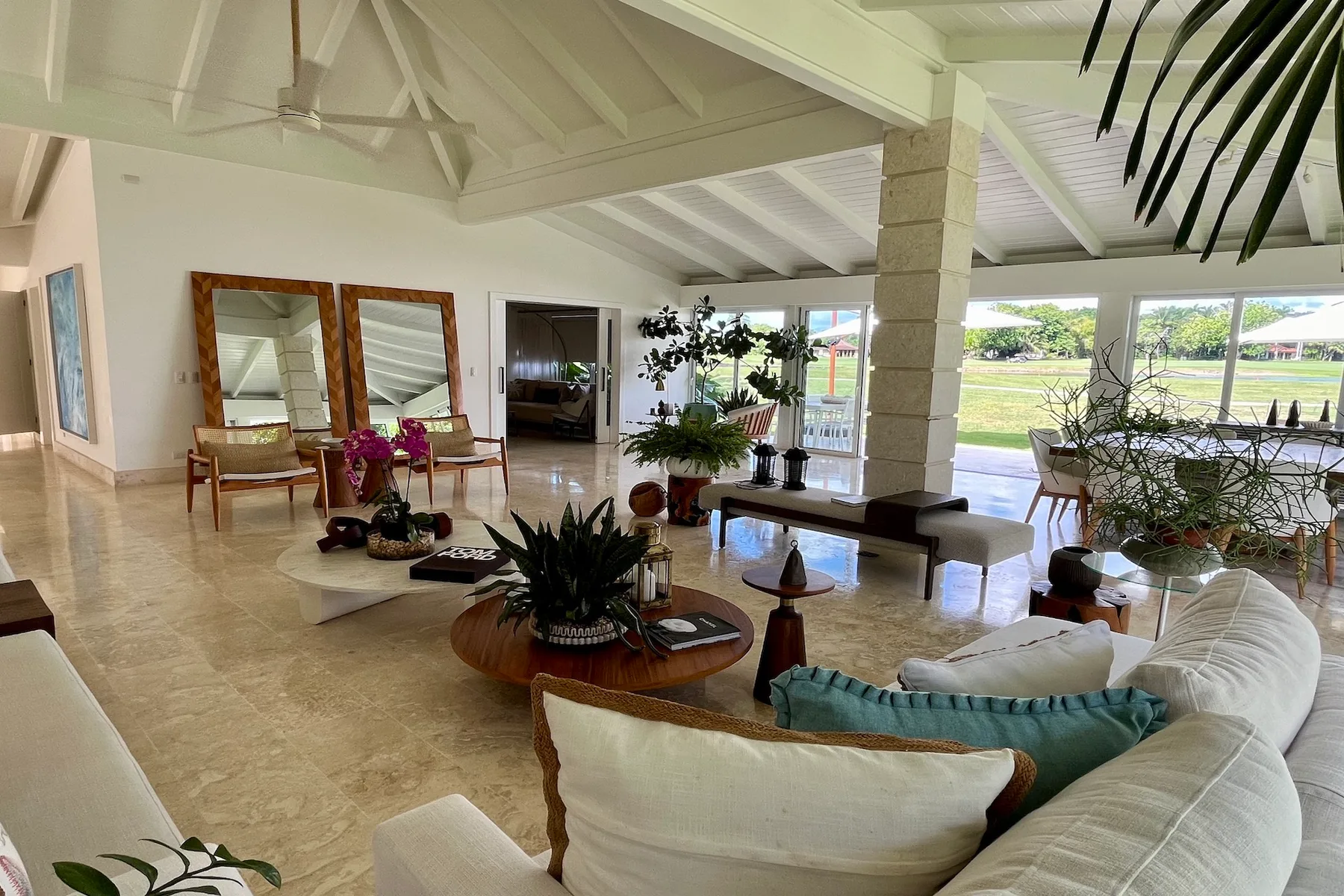 Una sala luminosa con asientos, plantas de interior y grandes ventanas con vistas a la vegetación.