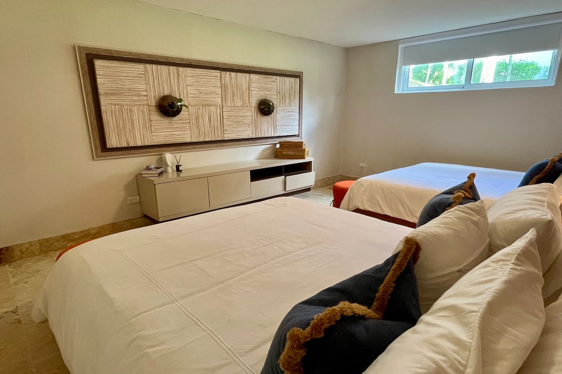 Un dormitorio con dos camas y un mueble bajo bajo una decoración de pared.