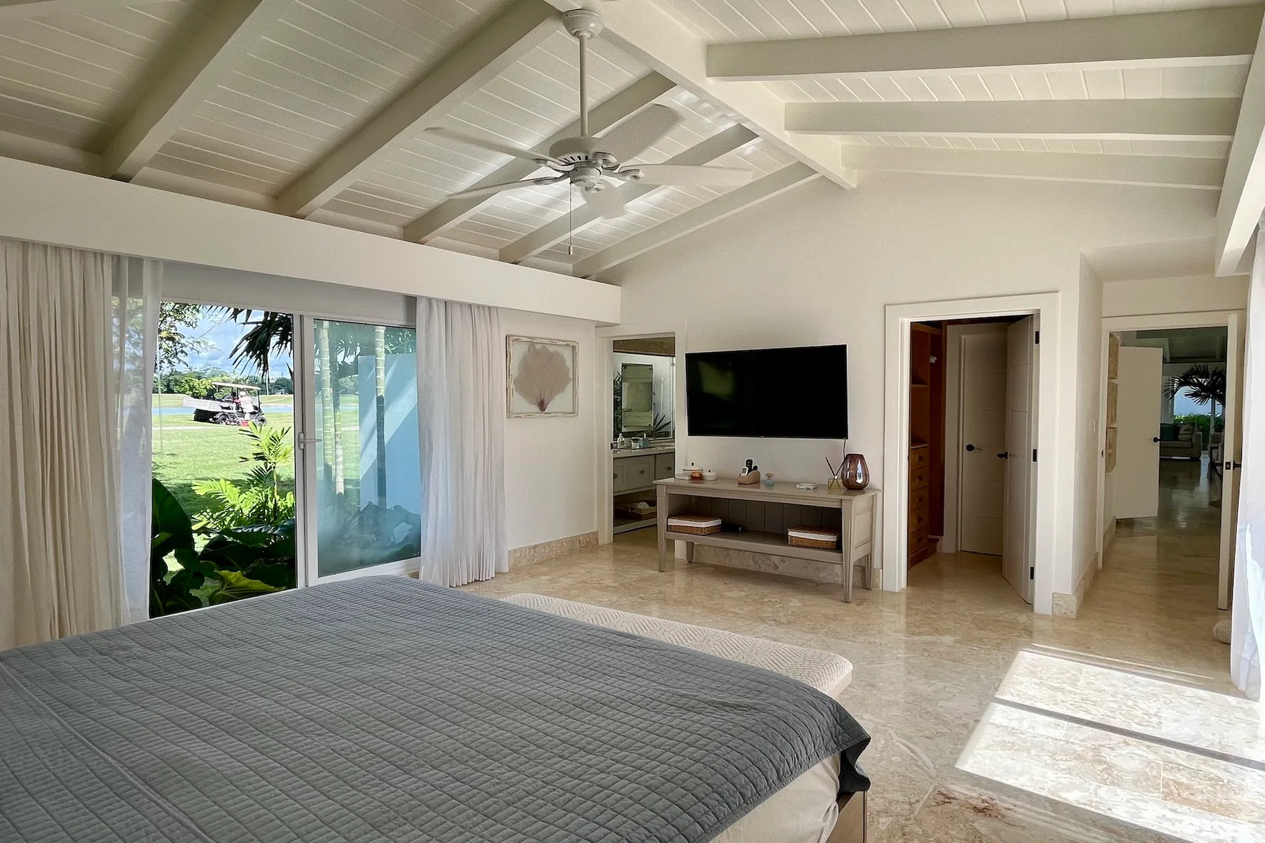 Un dormitorio luminoso con una cama grande, un televisor y puertas corredizas de vidrio.