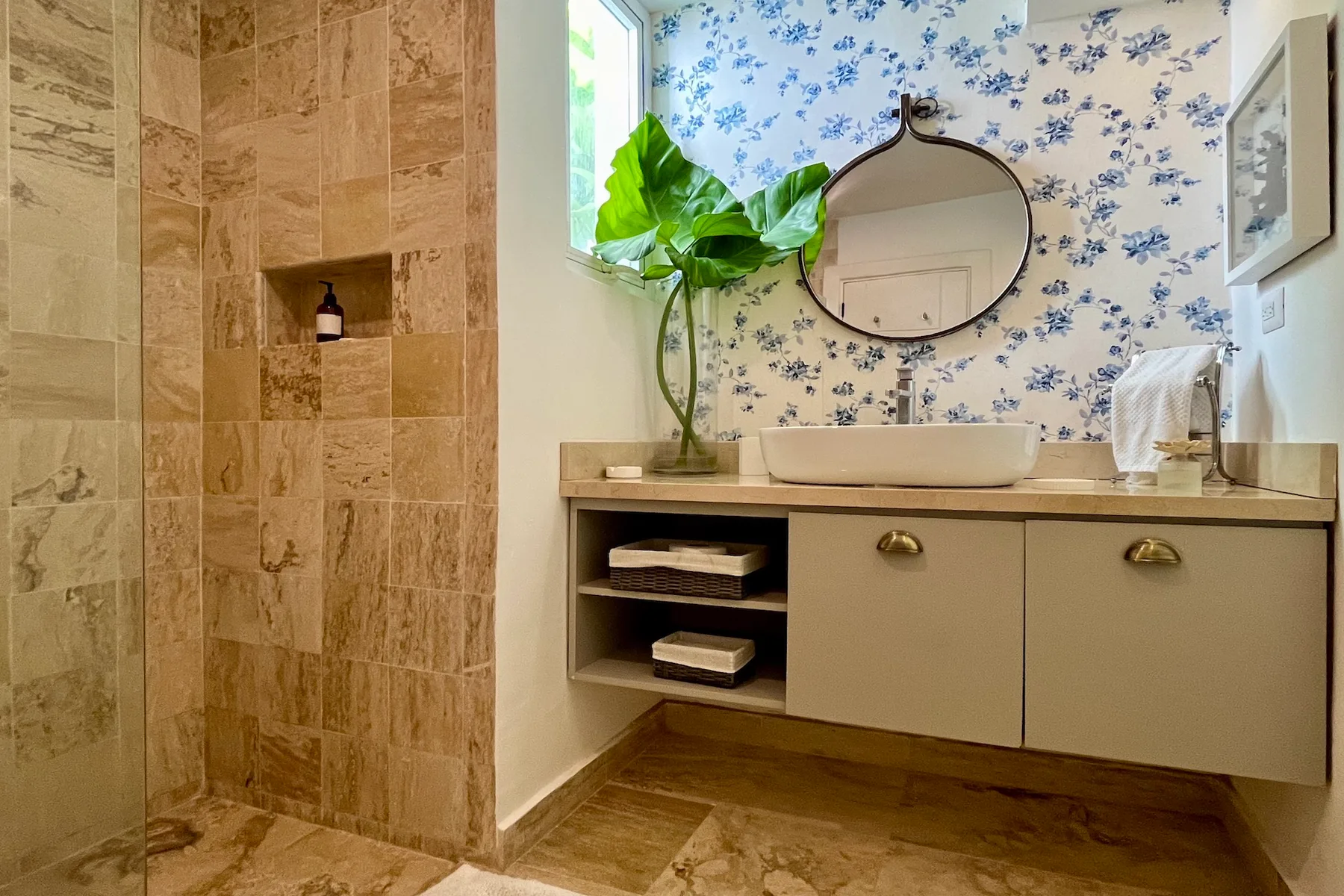 Un tocador de baño con lavabo sobre encimera y una zona de ducha revestida de azulejos.
