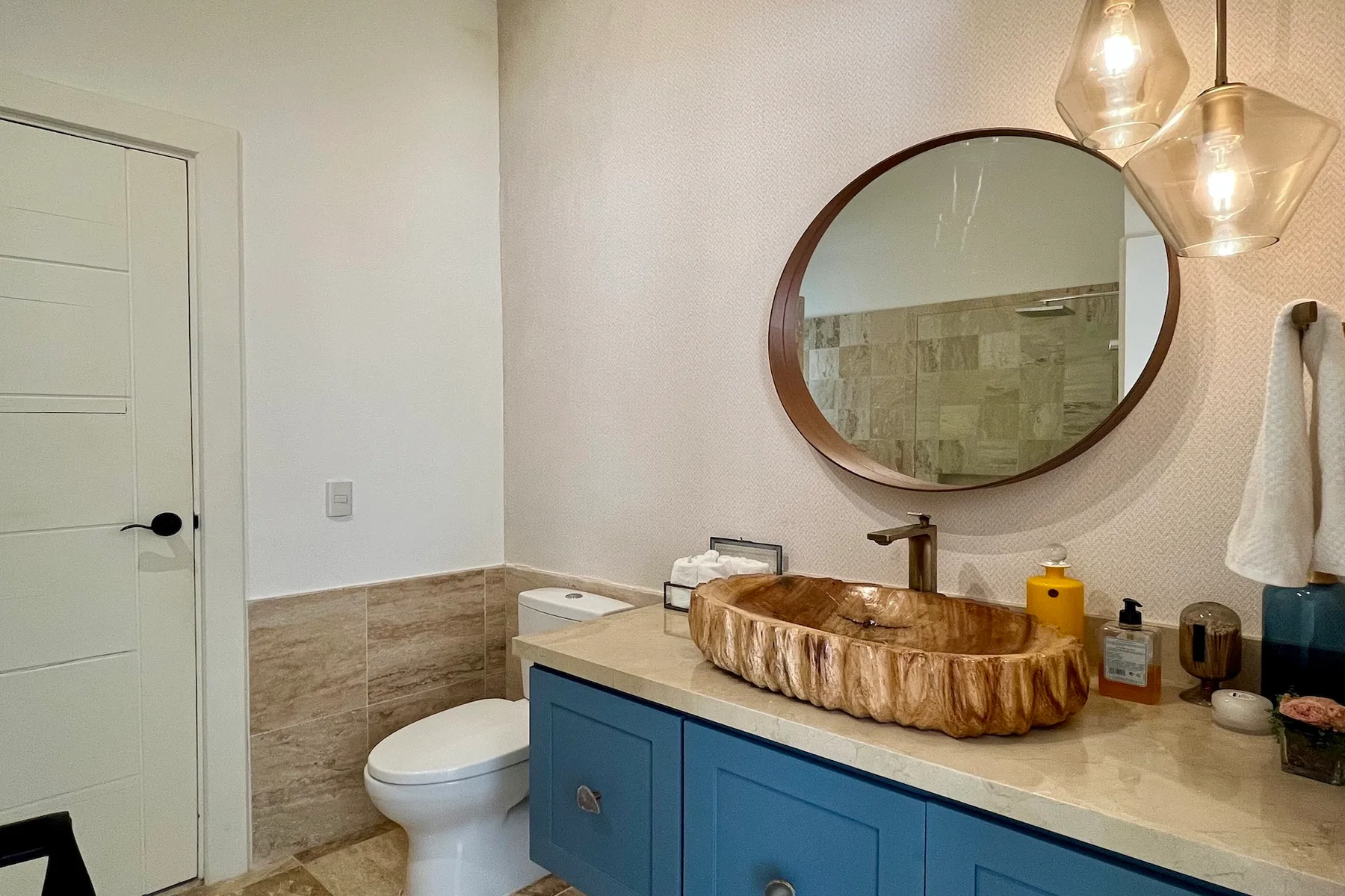 Un tocador de baño con un lavabo sobrepuesto y un espejo redondo.