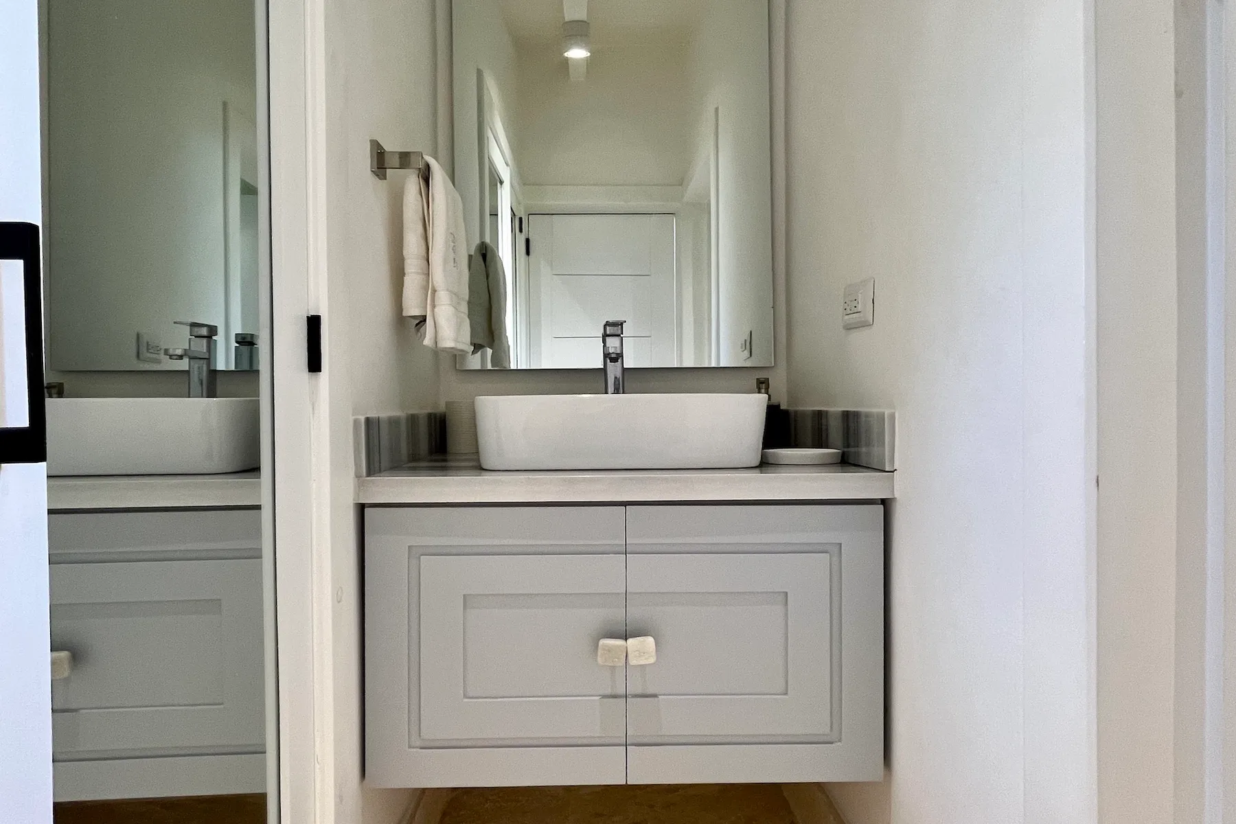 Un tocador de baño con un espejo amplio y un lavabo blanco sobre la encimera.