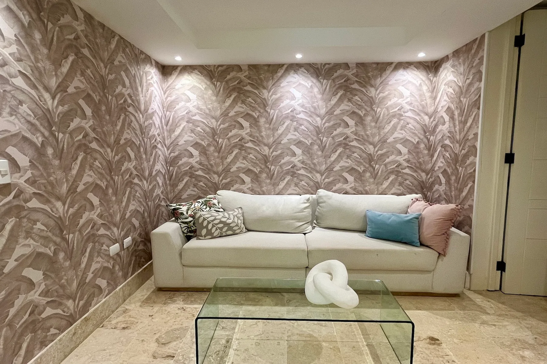 Una sala de estar con un sofá claro y una mesa de centro de vidrio.