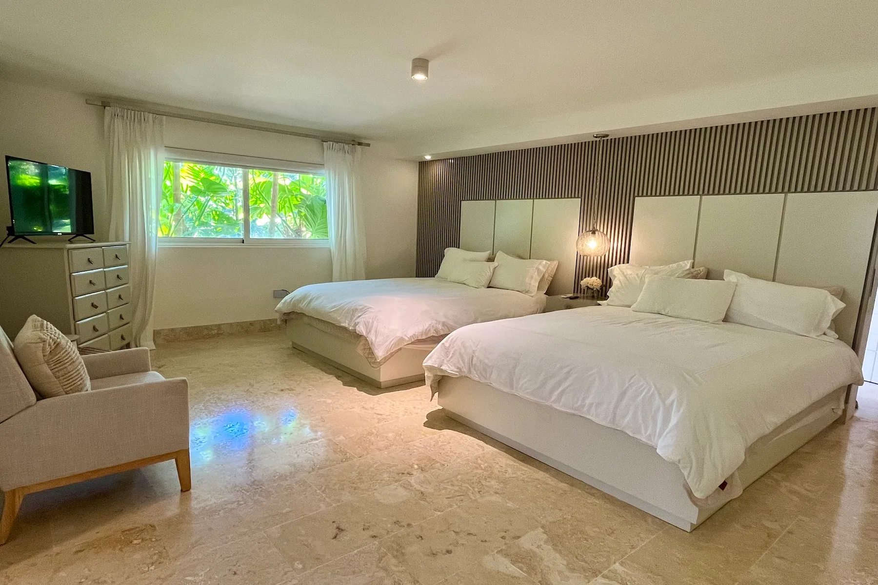 Un dormitorio con dos camas, una ventana y un televisor.