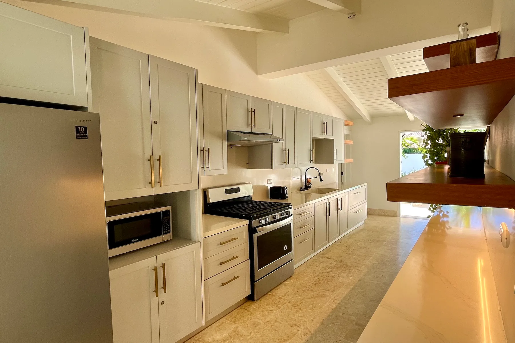 Una cocina luminosa con gabinetes claros, una estufa y una encimera larga.
