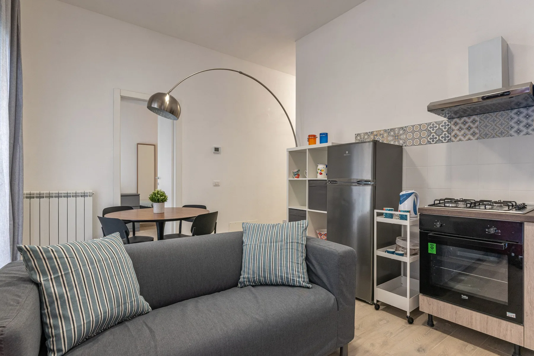 A living area opens onto a compact kitchen, with a sofa in the foreground.