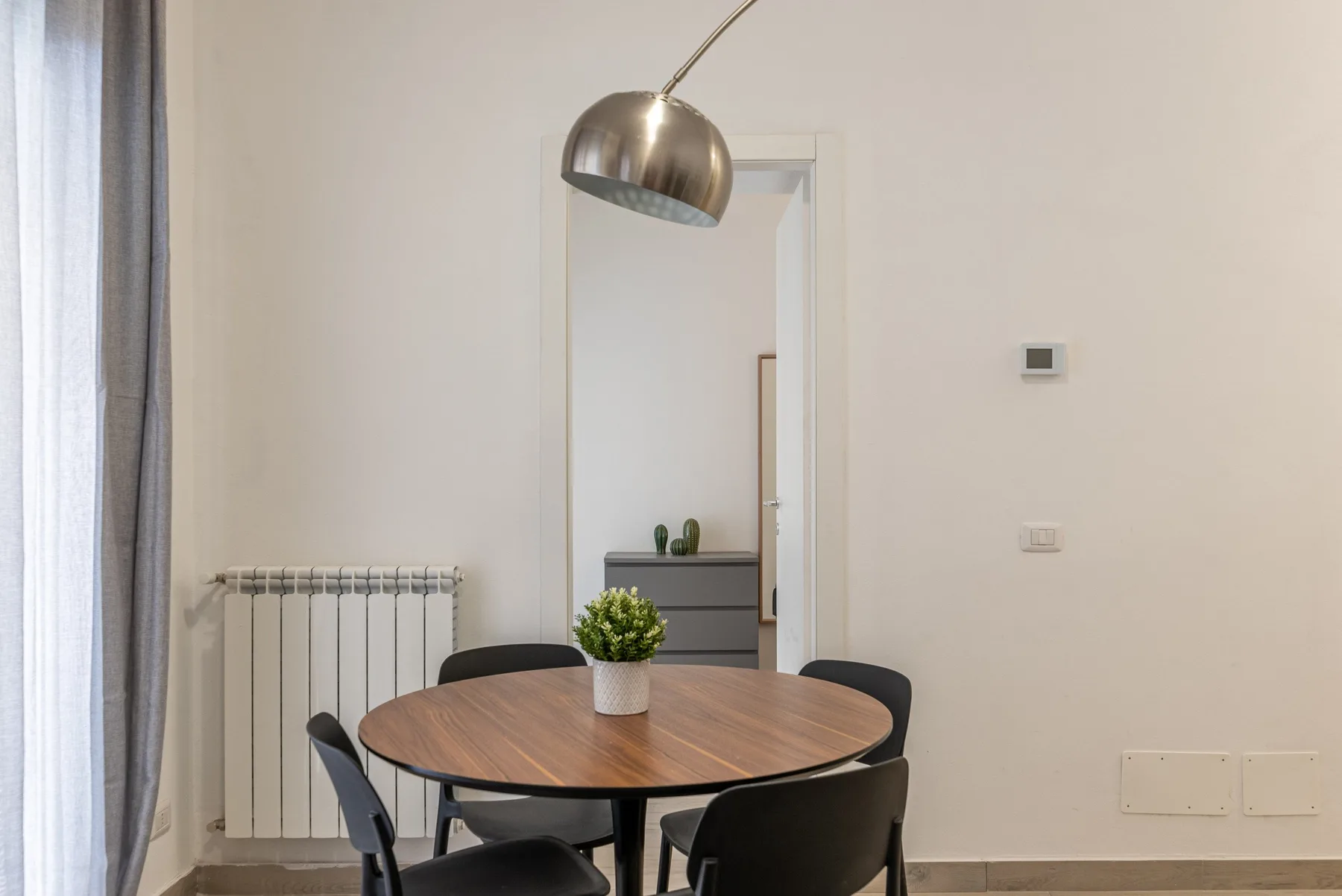 Comedor con una mesa redonda de madera y sillas junto a una ventana con cortinas.