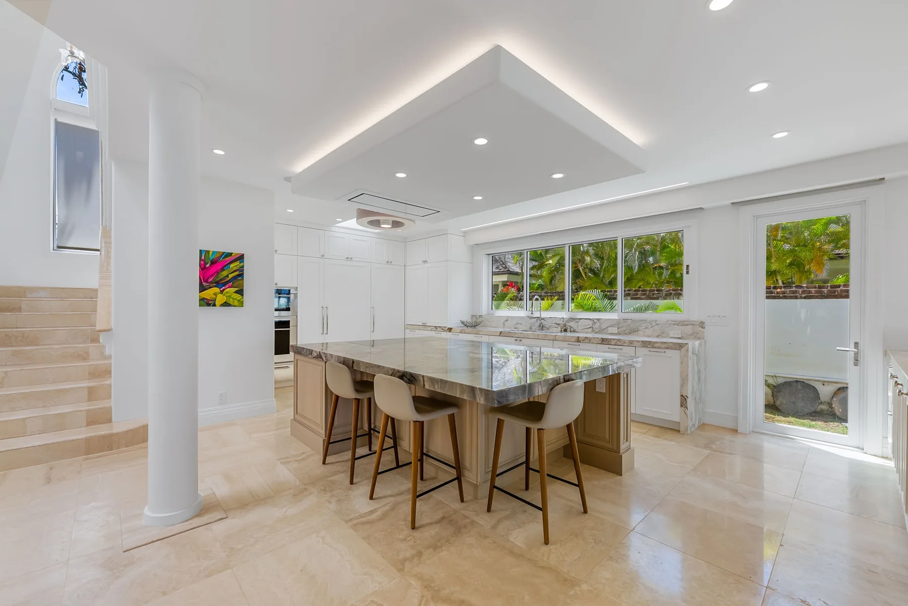 Una cocina luminosa con una gran isla y ventanas con vistas a la vegetación.