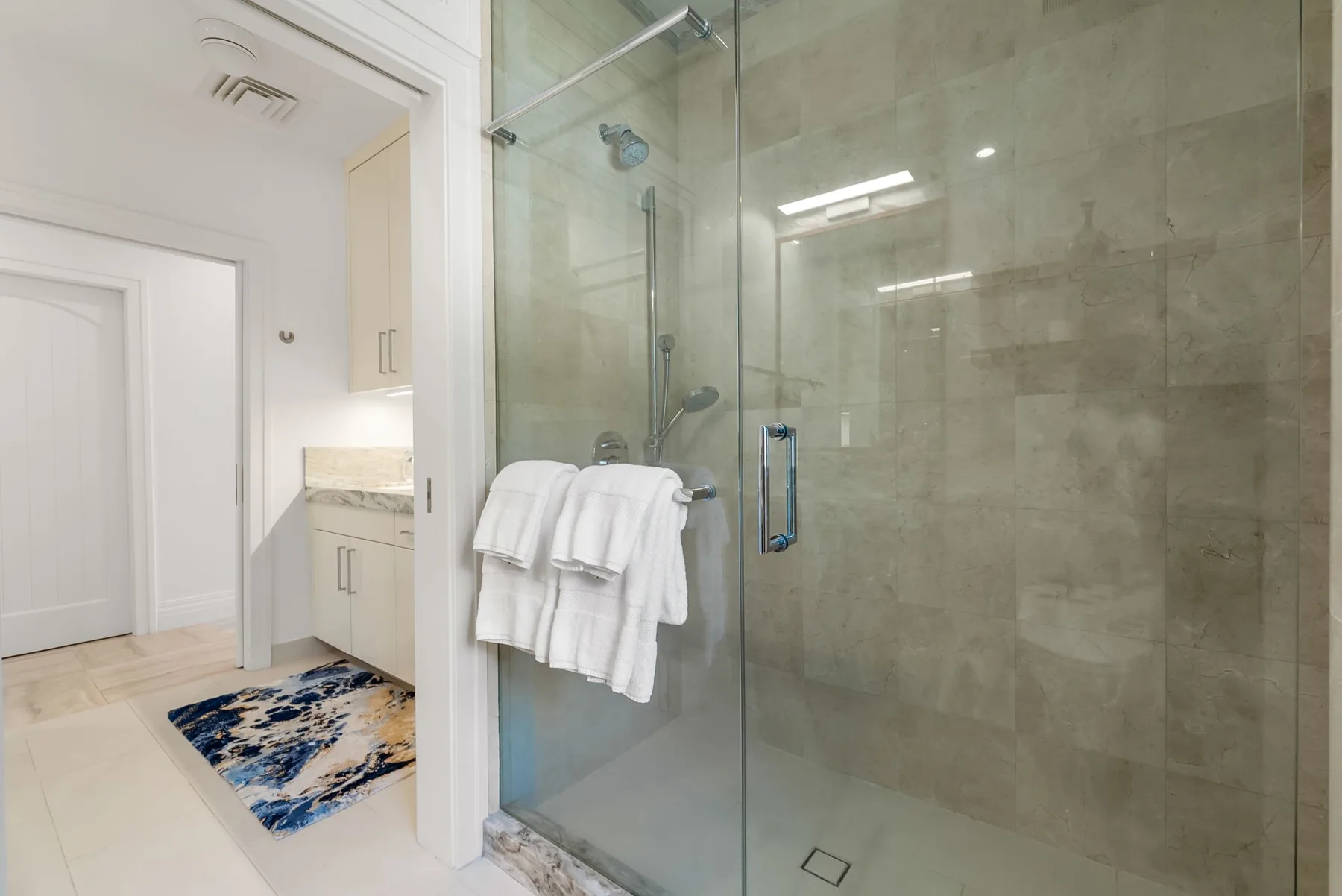 Un baño con una ducha de vidrio y toallas blancas.