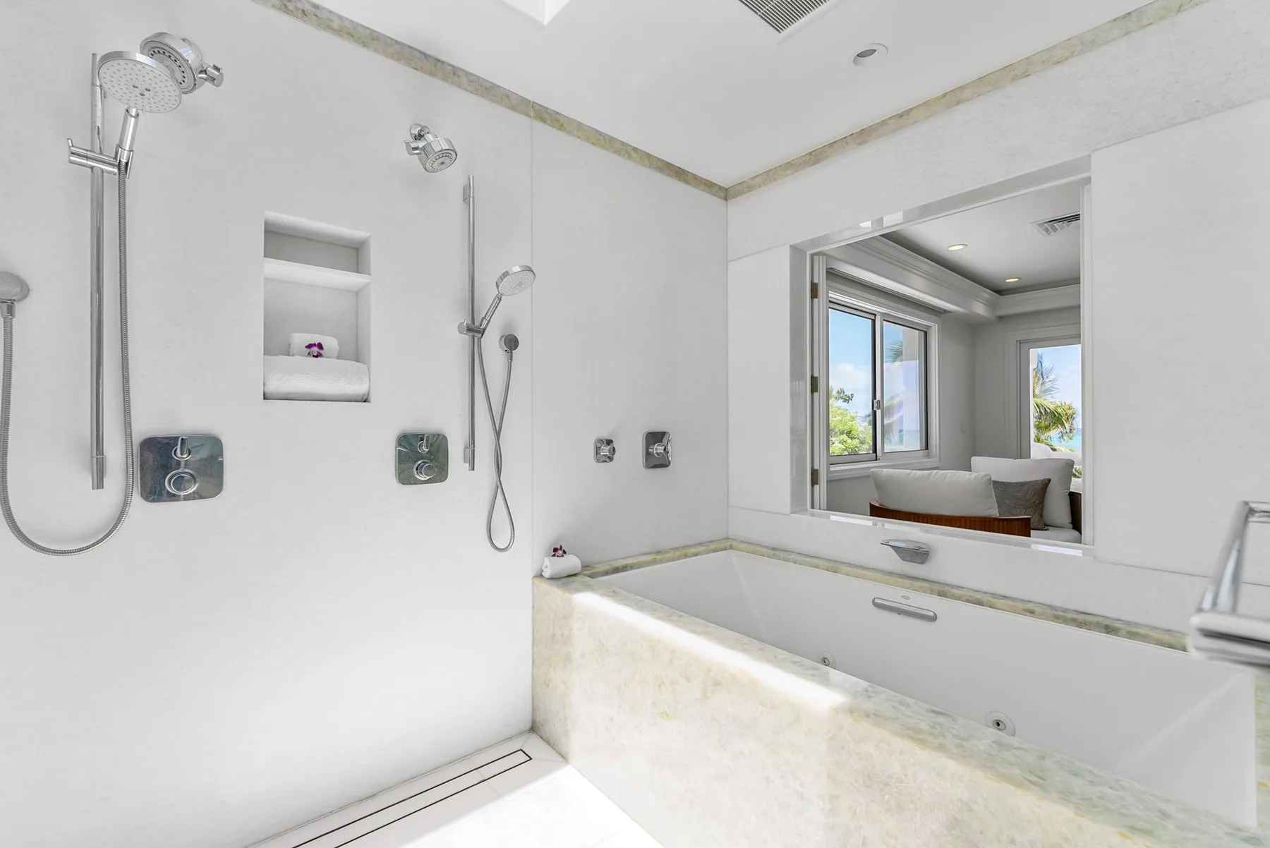 Un baño luminoso con bañera, accesorios de ducha y un espejo grande.
