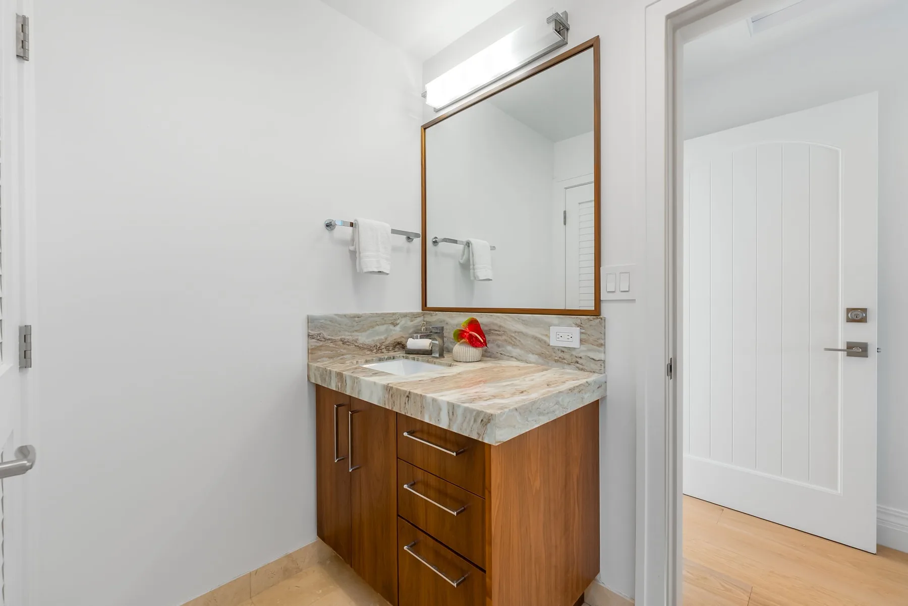 Un tocador de baño con un espejo grande y una encimera con vetas de mármol.