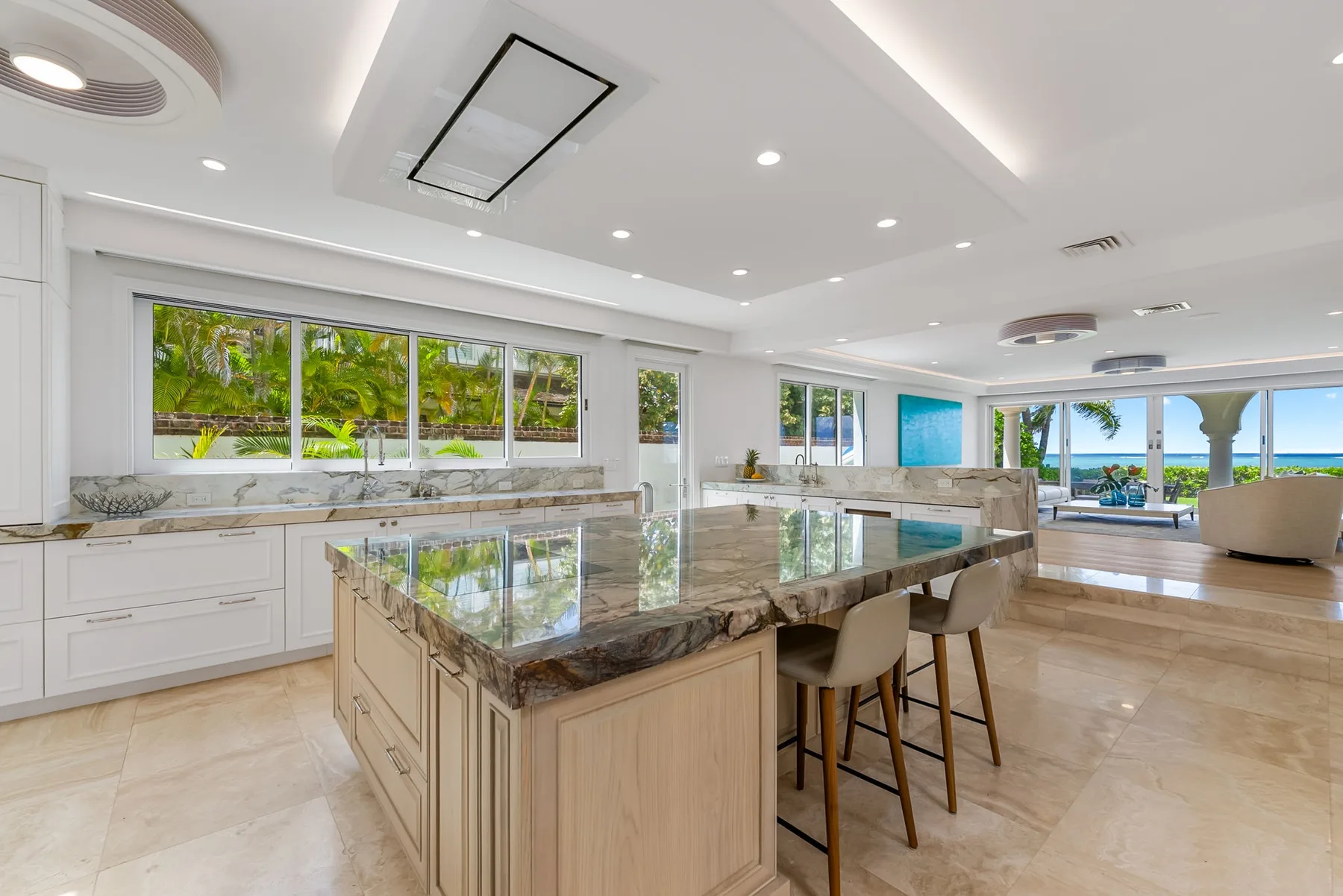 Una cocina abierta y luminosa con una isla grande y ventanas con vistas a la vegetación y al agua.