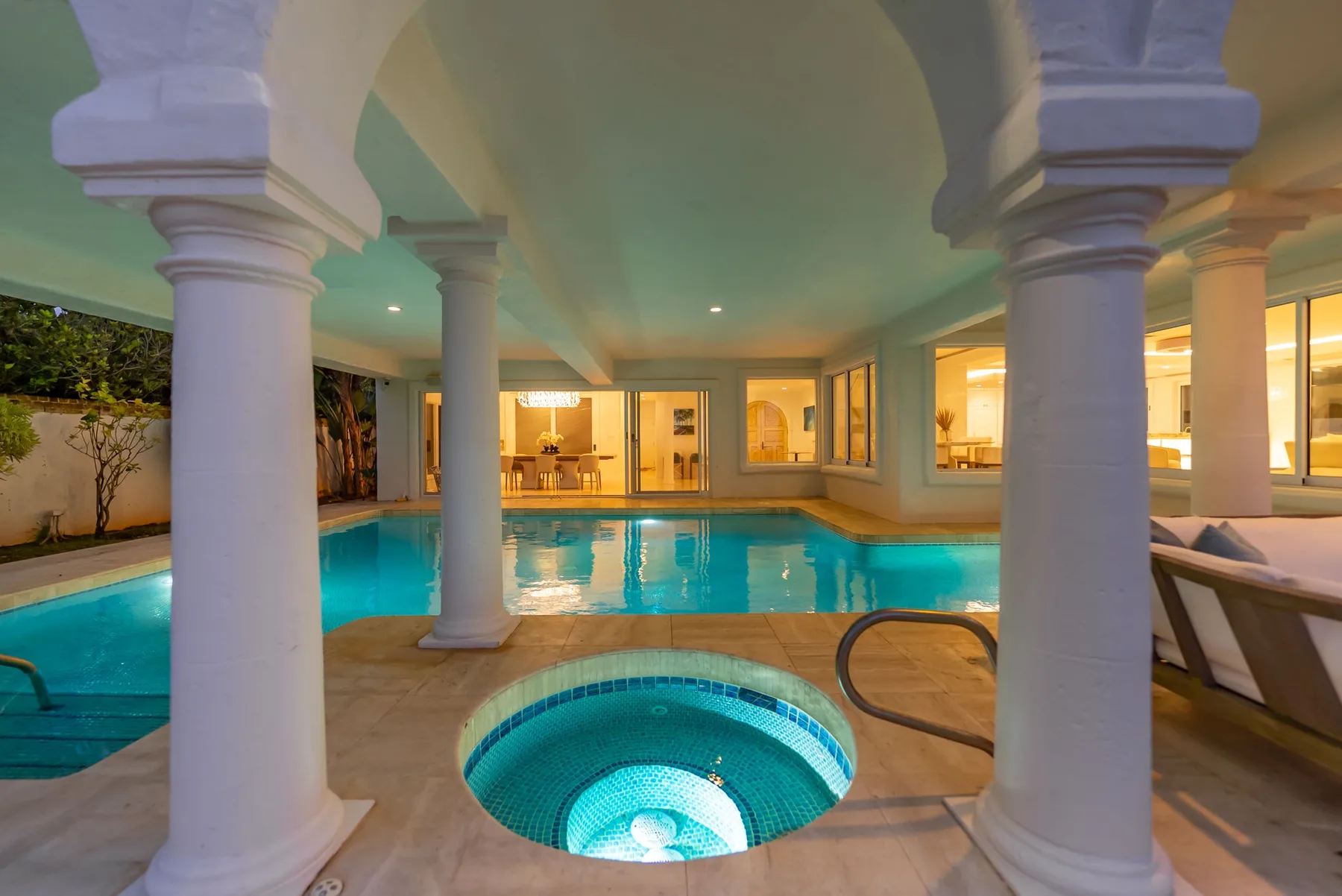 Una piscina interior con un pequeño spa circular en primer plano.