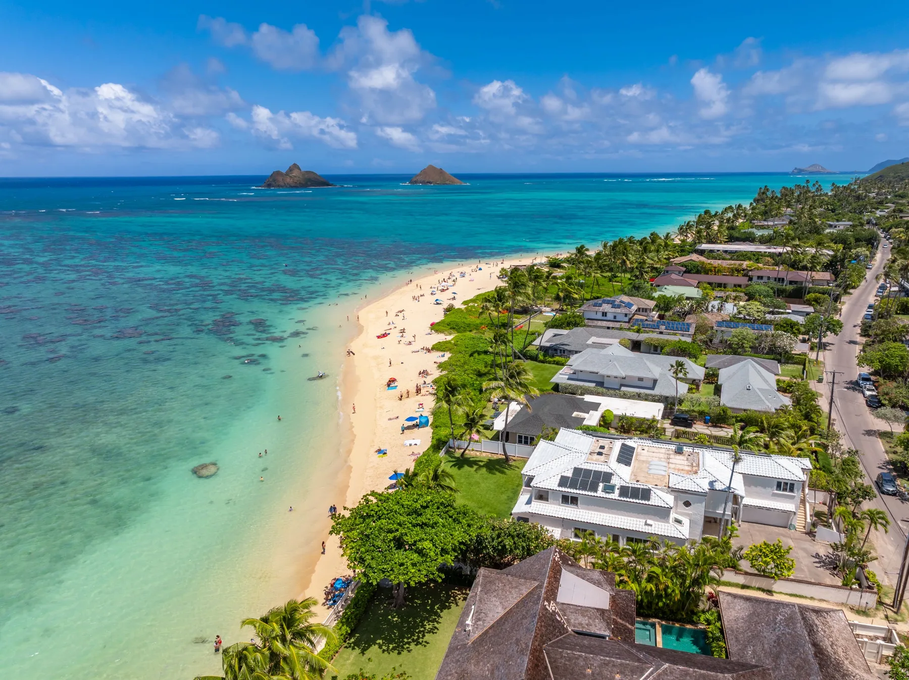 Vista aérea de una playa tropical junto a aguas turquesas y un barrio costero.