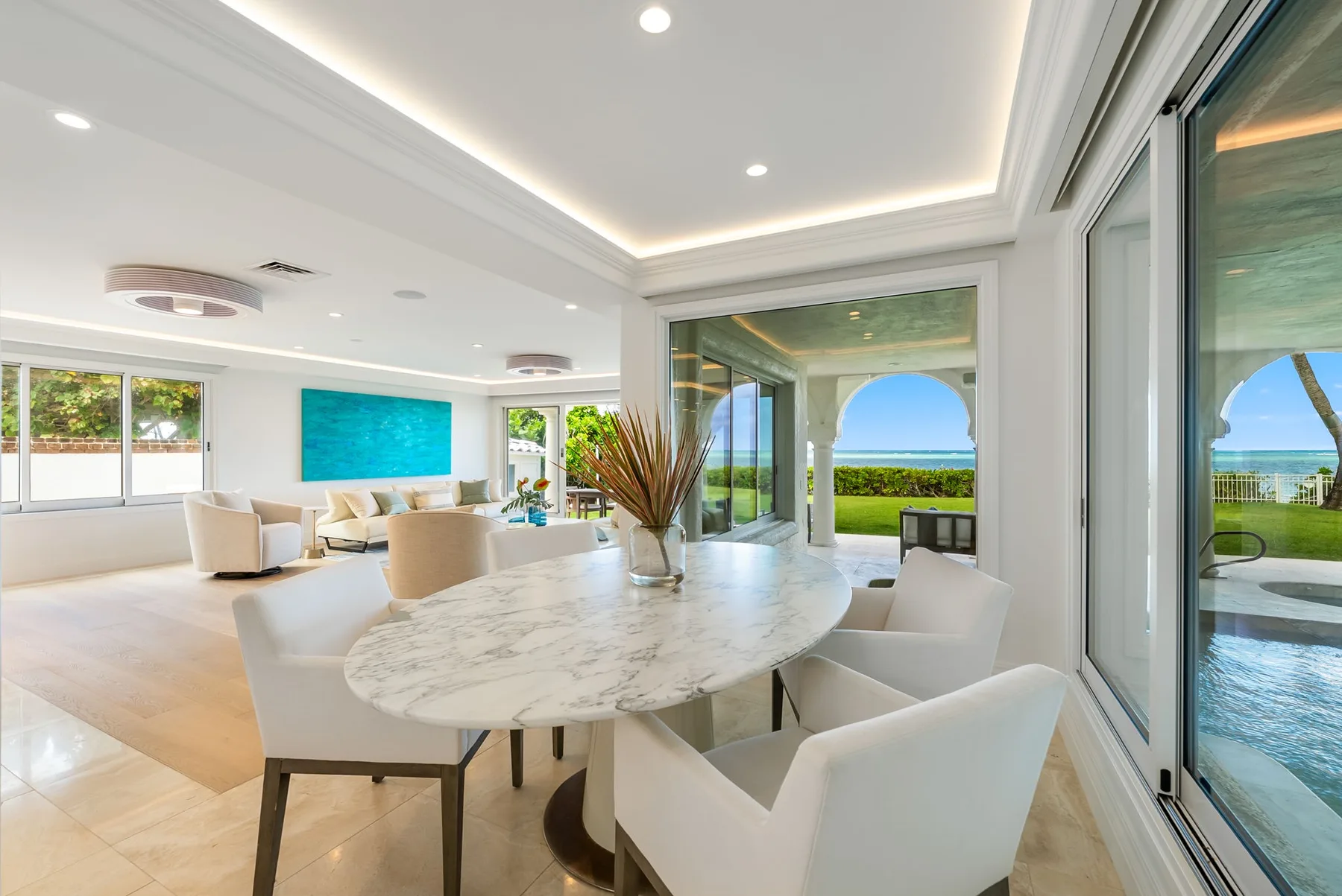 Un comedor y sala de estar diáfanos y luminosos, con una mesa ovalada junto a grandes ventanales.