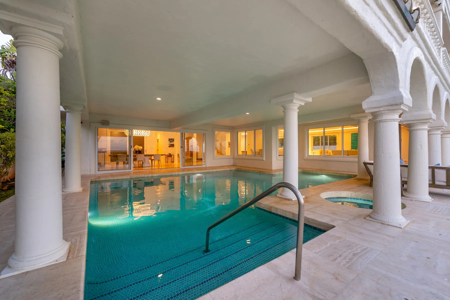 Una piscina interior está rodeada de columnas y ventanas iluminadas.