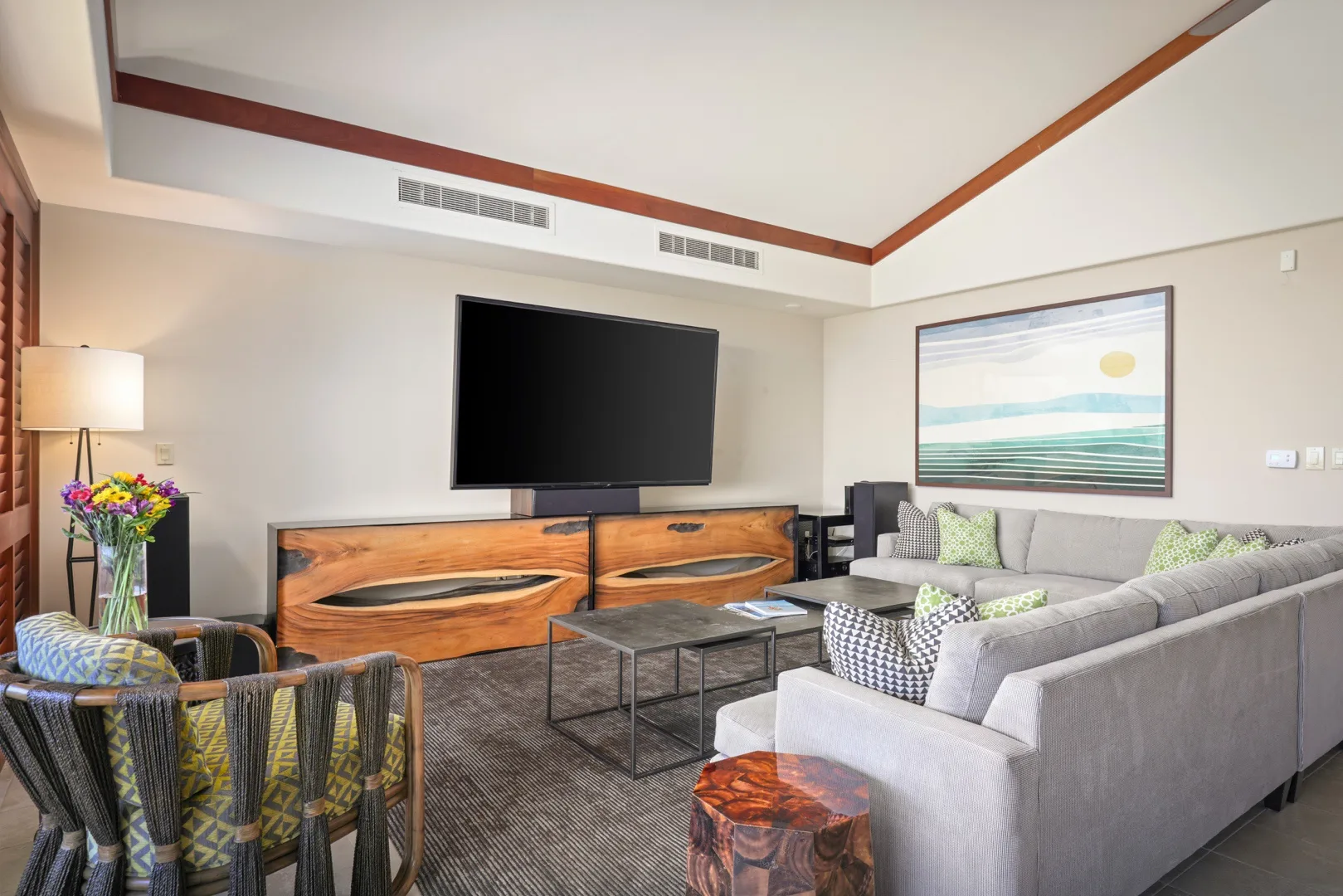 Una sala de estar con un televisor grande, asientos y una mesa de centro.