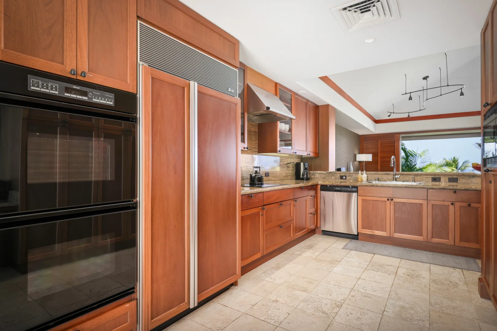 Una cocina con gabinetes de madera, electrodomésticos empotrados y una isla central.