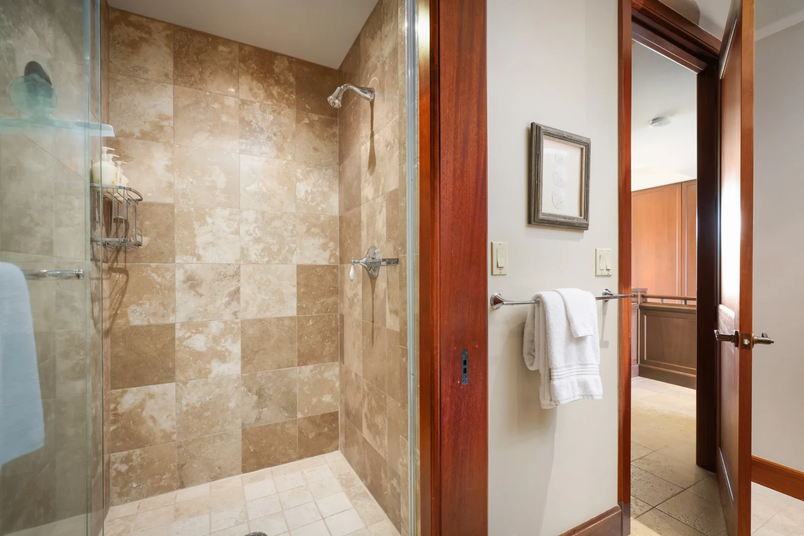 Un baño con azulejos, una ducha de vidrio y una toalla junto a la puerta.