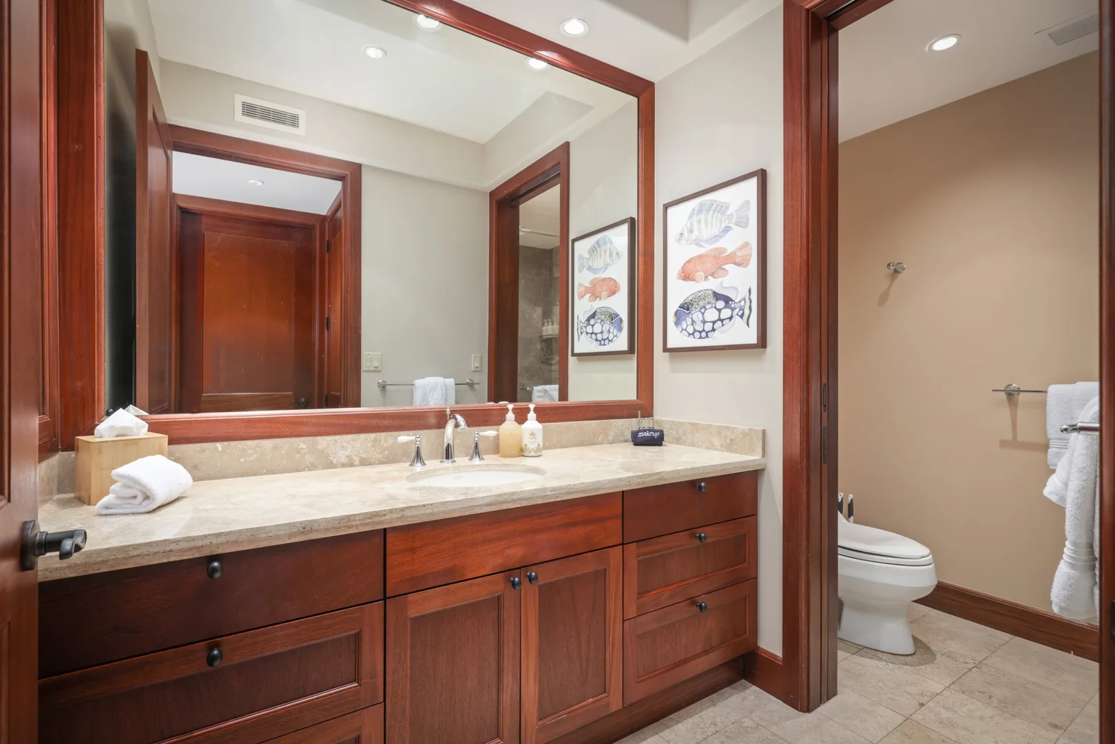 Un tocador de baño con un espejo amplio y gabinetes de madera.