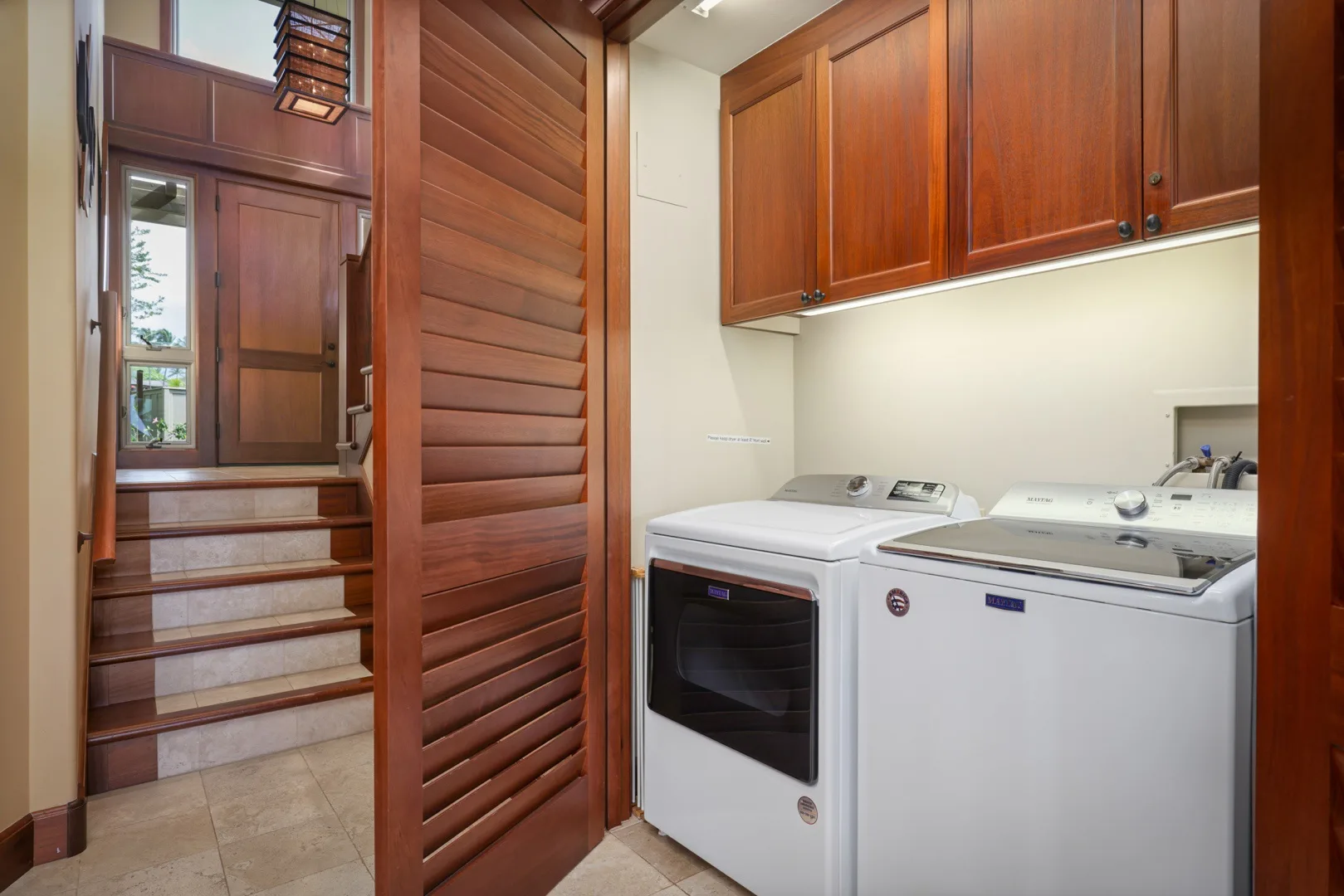 Un cuarto de lavandería con lavadora y secadora bajo gabinetes de madera.